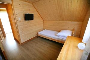 a small wooden room with a bed and a television at Domki ELDORADO in Dębki