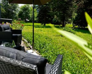 a patio with two chairs and an umbrella in the grass at Ferienwohnungen BERGfeeling in Bad Mitterndorf