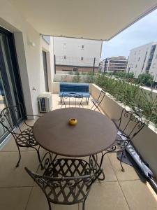 einen Tisch und Stühle auf dem Balkon eines Apartments in der Unterkunft APPARTEMENT TYPE 2 NEUF +GRANDE TERRASSE in Le Lavandou + 3 Fotos