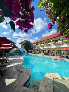 a swimming pool in a resort with purple flowers at Marine Bay Sanur in Sanur