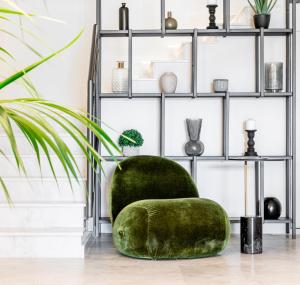 a green chair in a room with shelves at The Londoner Hotel Sliema in Sliema