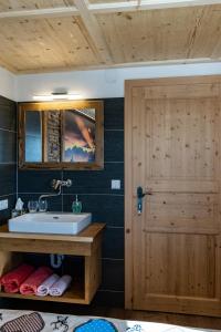 a bathroom with a sink and a wooden door at Almgasthaus Glocknerblick in Großkirchheim