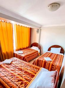 two beds in a hotel room with orange curtains at Mallmanya Inn in Cusco