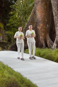 two women standing on a walkway in front of a tree at Taj Exotica Resort & Spa, Andamans in Havelock Island