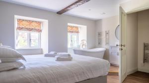 a white bedroom with a bed and a tub and a sink at Cunsey Mill House in Far Sawrey