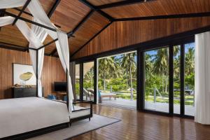 a bedroom in a villa with a bed and sliding glass doors at Taj Exotica Resort & Spa, Andamans in Havelock Island