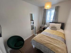 a bedroom with a bed and a green chair at Corby Guest House in Corby