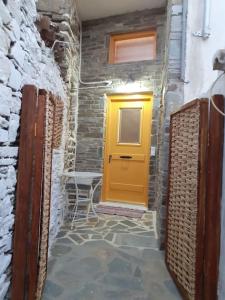 a yellow door in a stone building with a chair at Traditional Katafiki home in Kithnos