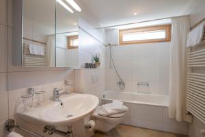 a bathroom with a sink and a toilet and a tub at Haus Bella Vista in Riederalp