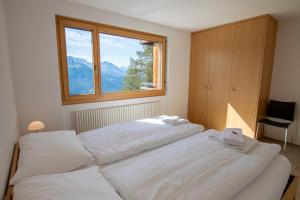 2 weiße Betten in einem Schlafzimmer mit Fenster in der Unterkunft Apartment Bella Vista in Riederalp