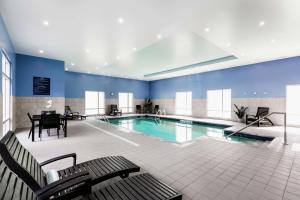 - une grande piscine avec une table et des chaises dans l'établissement Hampton Inn & Suites by Hilton Québec - Beauport, à Québec