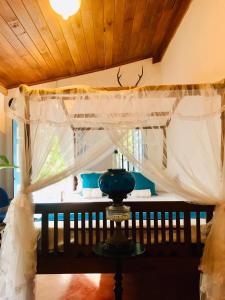 a bedroom with a bed with a curtain and a table at Museum Villa 09 in Beruwala