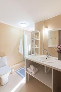 a white bathroom with a toilet and a sink at New Apt Close to Medical Center with Garden in Heraklio Town