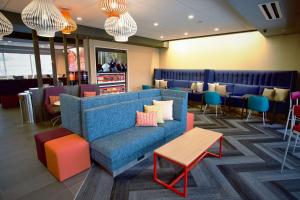 a lobby with a blue couch and tables and chairs at Tru By Hilton Oklahoma City Nw Expressway in Oklahoma City