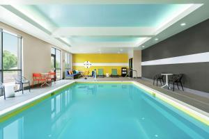 a pool in a hotel room with chairs and tables at Tru By Hilton Hershey Chocolate Avenue in Hershey