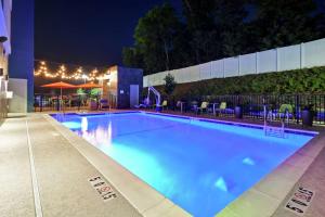 Home2 Suites By Hilton Birmingham/Fultondale, Al في فولتونديل: مسبح كبير في الليل مع كراسي ومظلات