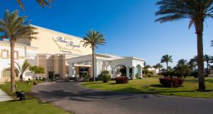 a building with palm trees in front of a street at Palm Royale Resort - Soma Bay in Hurghada