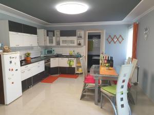 a kitchen with white cabinets and a table with chairs at Százszorszép Vendégház in Csongrád