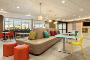 Home2 Suites By Hilton Portland Airport في بورتلاند: غرفة معيشة مع أريكة وطاولات وكراسي