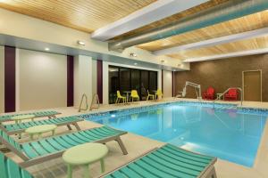a pool in a hotel room with chairs and tables at Home2 Suites By Hilton Portland Airport in Portland