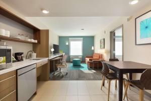 eine Küche und ein Wohnzimmer mit einem Tisch und Stühlen in der Unterkunft Home2 Suites By Hilton Portland Airport in Portland