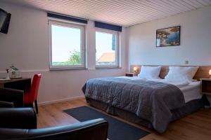 a bedroom with a large bed and two windows at Hotel zur Post Ochsendorf in Königslutter am Elm
