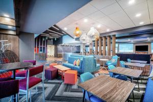 Tru By Hilton Greenville في غرينفيل: مطعم به طاولات وكراسي وطاولات ملونة