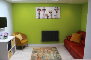 a living room with green walls and a red couch at Modern Property Near Chichester & Goodwood Events with Garden, Great for Families! in Chichester