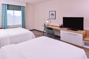 a hotel room with two beds and a desk with a television at Hilton Garden Inn Kansas City Airport Mo in Kansas City