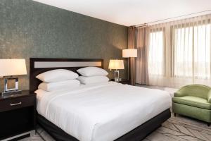 a bedroom with a large white bed and a green chair at DoubleTree by Hilton Newark Penn Station, NJ in Newark