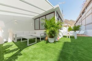 un patio con muebles blancos y césped verde en The Terraces Luxury Penthouses, 3B, en Santa Cruz de Tenerife