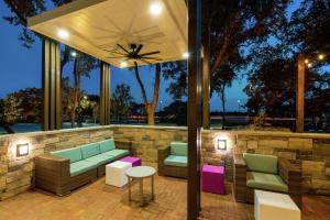 Elle comprend une terrasse dotée d'un mobilier vert et rose ainsi que d'un mur en pierre. dans l'établissement Hilton Garden Inn Cedar Park Austin, à Austin