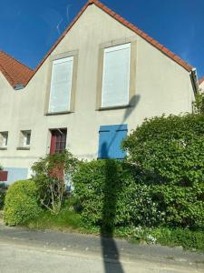 维桑Belle maison de famille - Wissant的一栋有两扇窗户、门前长着灌木丛的房子