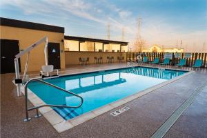 a swimming pool with blue chairs and a building at Home2 Suites Bakersfield in Bakersfield