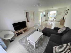 维桑Belle maison de famille - Wissant的客厅里有一张黑色沙发和一张桌子