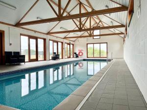 a large swimming pool in a building with windows at Hillcrest, Blythburgh in Blythburgh