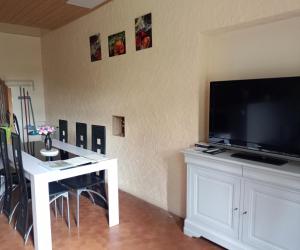 a living room with a large television and a table with chairs at Le Fouzon in Meusnes