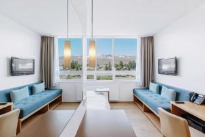 een woonkamer met blauwe banken en een groot raam bij Akureyri - Berjaya Iceland Hotels in Akureyri