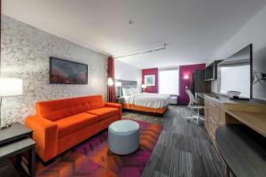um quarto de hotel com um sofá laranja e uma cama em Home2 Suites By Hilton Portland Hillsboro em Hillsboro