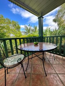 une table et une chaise assises sur une terrasse couverte dans l'établissement LES CASES METISSES, à Saint-Louis