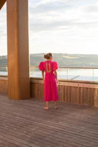Eine Frau steht auf einem Deck und blickt aufs Wasser hinaus. in der Unterkunft Wood Hotel by Frich's in Brumunddalen