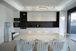 a white kitchen with a table and white chairs at Villa Zulfikar in Mostar