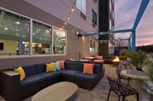 a patio with a blue couch and tables and chairs at Tru By Hilton Mobile in Mobile