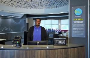 a man standing behind a counter in a restaurant at Tru By Hilton Mobile in Mobile