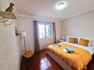 een slaapkamer met een bed met gele lakens en een raam bij House Levada in Ponta Delgada