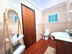 een badkamer met een wastafel, een toilet en een spiegel bij House Levada in Ponta Delgada