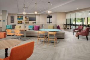 a waiting room with a couch and tables and chairs at Home2 Suites By Hilton St. Augustine I-95 in St. Augustine