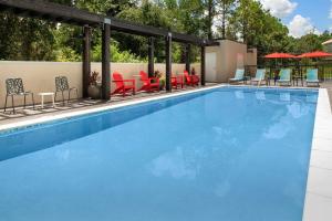 uma piscina com cadeiras, mesas e guarda-sóis em Home2 Suites By Hilton St. Augustine I-95 em Saint Augustine