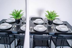 a black table with chairs and plates and plants on it at Beautiful apartment una in Litherland