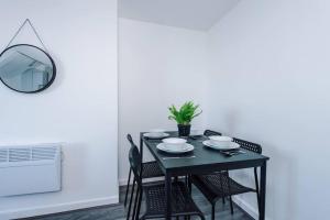een zwarte eettafel met stoelen en een spiegel bij Beautiful apartment una in Litherland